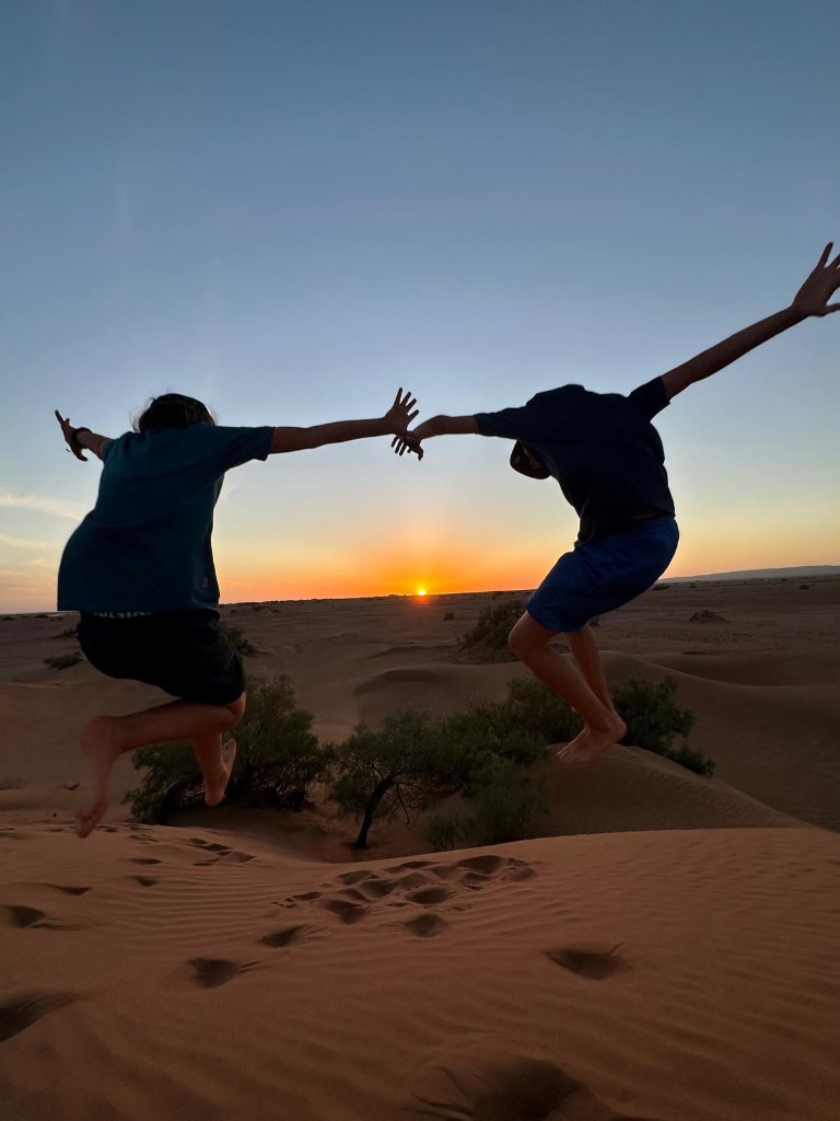 Travelers jumping in silhouette at sunset